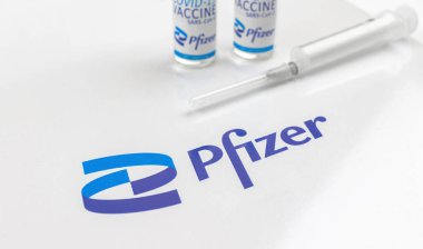 Kharkov, Ukraine - April 18, 2021: Pfizer logo close-up with vaccine vials on white glass table in a hospital