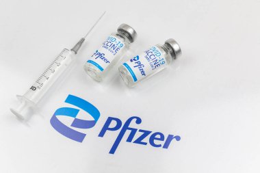 Kharkov, Ukraine - April 18, 2021: Pfizer COVID-19 vaccine vials by Biontech, backgrond with logo and medical syringe, vaccination concept photo