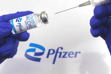 Kharkov, Ukraine - April 18, 2021: Doctor make vaccination by using Pfizer COVID-19 vaccine vials, close up with logo