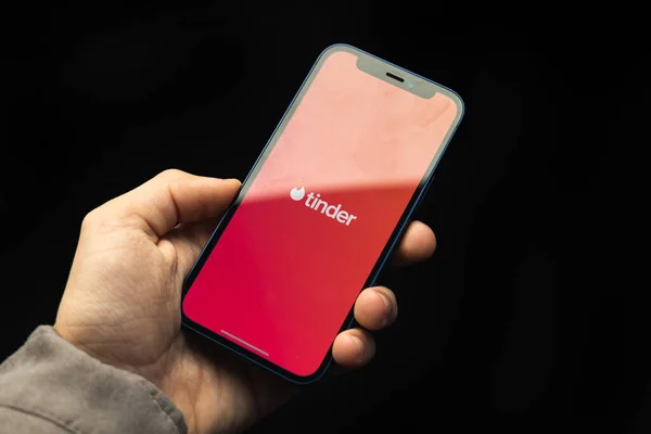 Kharkov, Ukrayna - 20 Nisan 2021: Tinder uygulaması, online flört hizmeti, logo ve simge ile Apple iPhone 'u elinde tutan adam