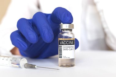 COVID-19 aşısını sunan doktor, Coronavirus tedavisi konsepti, mavi eldivenler, aşı şişesi, yakın plan, hastane ve tıp geçmişi fotoğrafı.