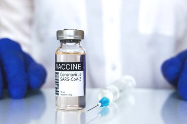 Beyaz elbiseli doktor covid-19 aşı tüpü, ilaç ve sağlık aşısı konseptini sunuyor. 