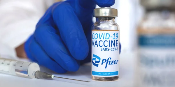 Kharkov, Ukrayna - 19 Nisan 2021: Pfizer COVID-19 aşı şişesi, doktor elinde cam şişe, afiş, hastane ve klinik geçmişi, sağlık ve aşı kavramı