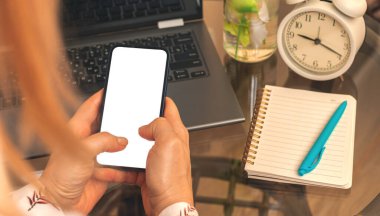 Akıllı telefon kullanan bir kadın, beyaz ekranlı bir model, sıcak ve rahat bir arka plan. 