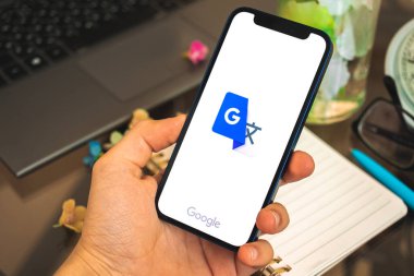 Kharkov, Ukrayna - 27 Nisan 2021: Elde Apple iPhone 12 akıllı telefonu, dil öğrenmek için Google çeviri uygulaması kullanan adam