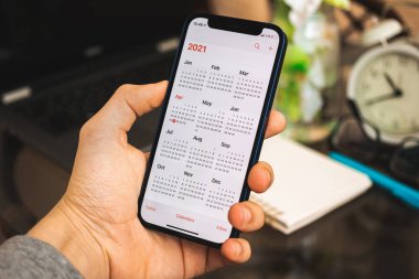 Kharkov, Ukrayna - 27 Nisan 2021: Man hold Apple iPhone 12, takvim uygulaması ekranda, takvim ekranda, 2021
