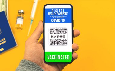 Akıllı telefon sahnesinde Covid-19 'a karşı aşılama sertifikası genç adamın elinde, salgın konsepti sırasında seyahat, yaz tatili fotoğrafı