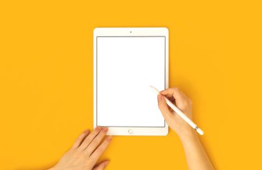 Kharkov, Ukrayna - 5 Mayıs 2021: Elma iPad 'in Modeli ve kadının elindeki stililus kalem, sarı parlak arkaplan ve üst görünüm 