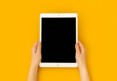 Kharkov, Ukrayna - 5 Mayıs 2021: Dijital tablet Apple iPad elinde, sarı zemin üzerinde maket ekran, üst görünüm 