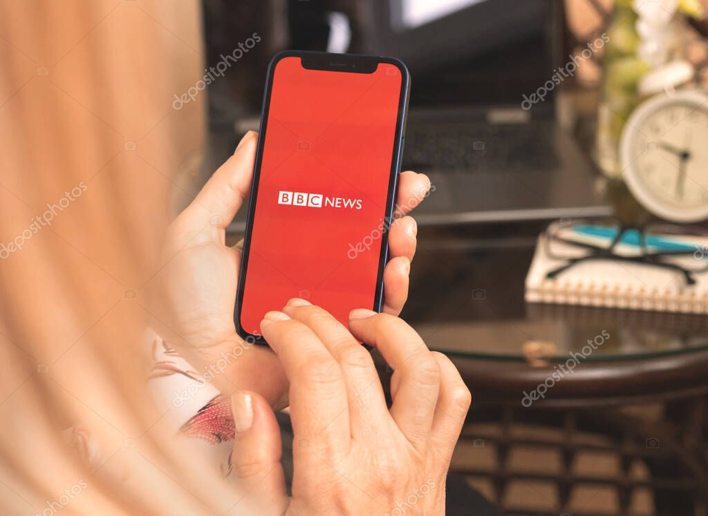 Kharkov, Ukraine - April 27, 2021: Woman use BBC News app on Apple iPhone screen, logo close up