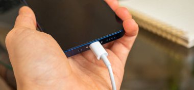 Kharkov, Ukrayna - 27 Nisan 2021: Adam Apple iPhone 12 Mini şarj etmek için yıldırım konnektörü kullanıyor