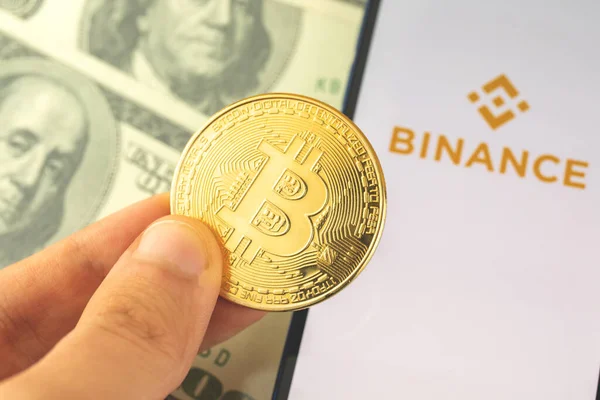 Харьков, Украина - 3 мая 2021 года: Binance bitcoin application on the screen, coin in hand, logo of app for buy and sell crypto curency — стоковое фото