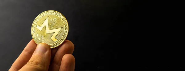 Monero coin in hand on black background, banner, business and finance concept, copy space photo