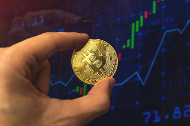 İşadamı bitcoin 'i grafiksel grafik arka planında, kripto takas ve ticaret konsepti iş fotoğrafında tutuyor