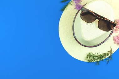 Fotokopi alanı fotoğrafı, hasır şapka ve güneş gözlükleriyle mavi arkaplanda düz yatıyordu.