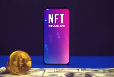 Kriptografik ve kriptografik, modern cep telefonu ekranında NFT logosu dolar ve kripto bitcoin ile ofis masası