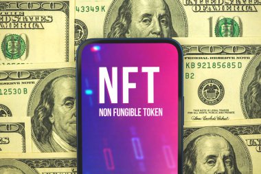 Kriptoart ve teknoloji kavramı, cep telefonundaki NFT logosu, yeni sanal kripto para birimi, bankacılık ve engelleme zinciri, arka planda dolar, üst görüş 