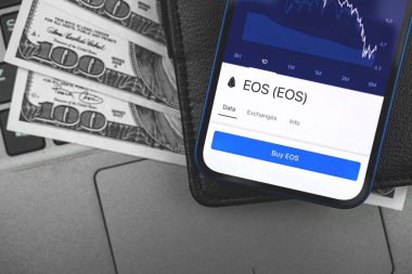 EOS crypto currency on the screen of mobile phone, online banking concept, investment and finance background with wallet and dollar