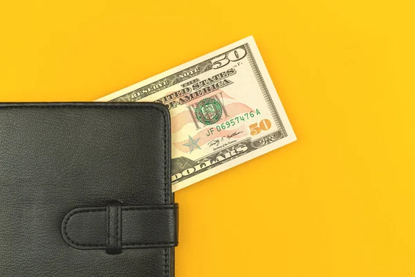 黄色の背景写真とオフィステーブルの上の黒い革の財布の小さな給与コンセプト 50ドル トップビューの写真 — ストック写真