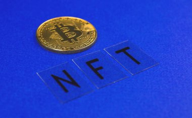 Bitcoin kripto para ve mavi ofis masasının arka planına yakın plan NFT harfleri