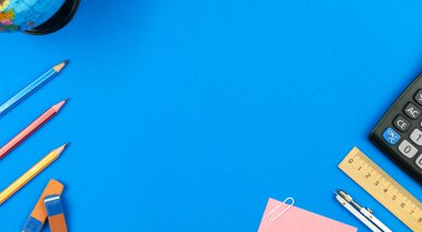 Kopya alanı olan okula geri dönüş sınır çerçevesi arka planı, mavi bir tabloda kırtasiye malzemesi olan eğitim kavramı, üst görünüm 