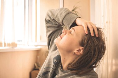 Tired girl freelancer resting on the veranda after hard and difficult day at work, holds her forehead with her hand with closed eyes
