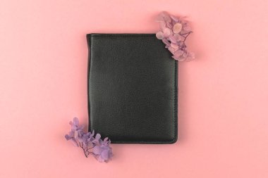 Kurumuş çiçek sınır kompozisyonu, pembe arkaplan, düz yüz ve üst görünümü olan siyah deri defter. 