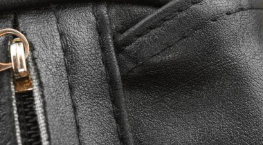 Siyah deri çanta, desen detaylı yüzey, dikişler arka plan.