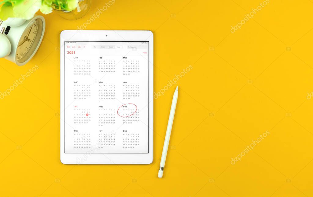 Tablet with September month 2021 calendar, yellow desktop background with copy space, top view 