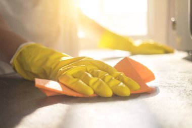 Evin mutfağındaki tezgahı sprey deterjanla temizleyen kadın.