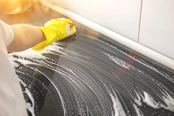 Closeup of worker in restaurant kitchen cleaning electric cooker after services