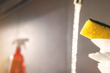 Mutfak su akışı ve üzerinde sarı sünger olan yıkanmamış bulaşıklarla dolu. Kopya alanı, seçici odak noktası.