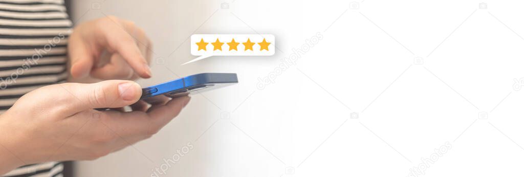 Woman hand pressing on smartphone screen with gold five star rating feedback icon, review the service business concept banner with copy space photo
