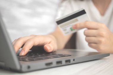 Elinde kredi kartıyla dizüstü bilgisayar kullanan bir kadın. Çevrimiçi alışveriş, harcama parası ve e-ticaret kavramı. İnternet bankacılığı arka planı 
