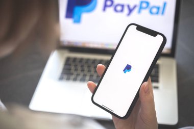Kharkov, Ukrayna - 12 Ağustos 2021: Paypal uygulaması. Ankesörlü telefon kullanan bir kadın. Marka logosu