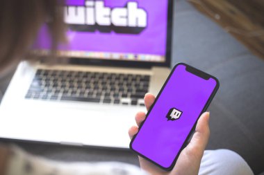 Kharkov, Ukrayna - 12 Ağustos 2021: Twitch uygulaması. Seğirme uygulaması olan akıllı telefon kullanan bir kadın. Marka logosu