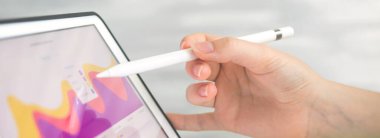 Kablosuz stil kalem kullanarak dijital tablet üzerindeki finansal sonuçları analiz eden kadın işçi. Ekranda iş diyagramı, ofis masası arka planı 