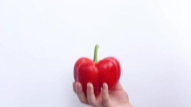 Kırmızı biberli el, kırmızı biber. Beyaz arka planda tatlı dolmalık biber tutan bir kadın.