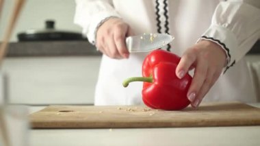 Şef bıçakla kesilmiş kırmızı tatlı biber dilimlenmiş mutfak tahtasının üzerinde 