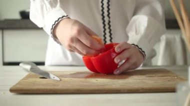 Ahşap kesim tahtasına kırmızı dolma biber dilimliyorum. Kadın eli kırmızı biber sebzelerini kesiyor. Sağlık yeme ve diyet gıda konsepti videosu