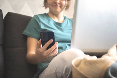 Güler yüzlü kız güz haftasonu evde bilgisayar ve bilgisayar kullanıyor. Ekim ayında modern cep telefonuyla el ele tutuşuyor.