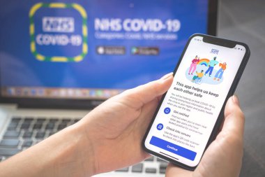 Kharkov, Ukrayna - 25 Ağustos 2021: Cep telefonu ekranında NHS COVID-19 uygulama logosu. NHS COVID-19 Coronavirus test uygulaması kullanan ve elinde akıllı telefon tutan bir kadın. 
