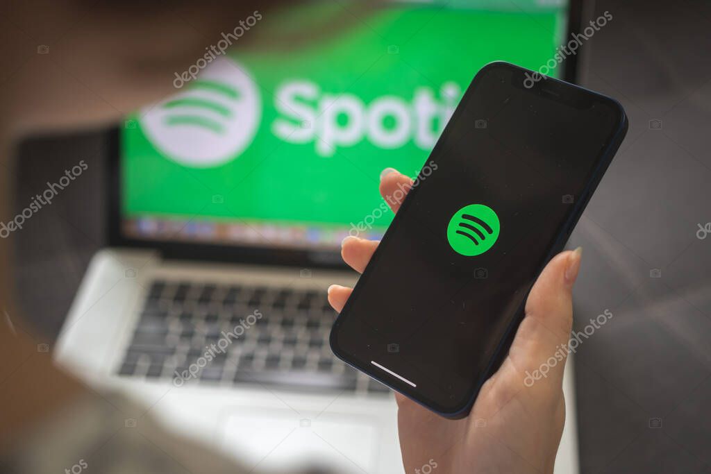 Kharkov, Ukraine - August 25, 2021: Woman using Spotify application and holding smartphone, close-up