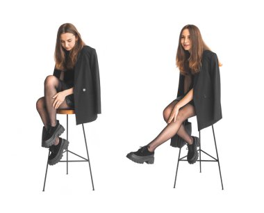 Beyaz arka planda izole edilmiş zarif siyah elbiseli neşeli bayan. Sandalyede oturan genç bir kadın.