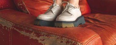 Kaliteli lüks mobilyalar ve modern şehir ayakkabıları genç kızda, yaşam tarzı kıyafet afişi arka planda kırmızı koltuklu fotoğraf.