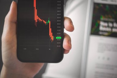 Hisse senedi ticaretiyle uğraşan biri. İş ve yatırım geçmişi fotoğrafı. Ekranda finansal grafikleri olan akıllı telefon. 