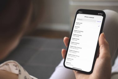 Kharkov, Ukrayna - 25 Ağustos 2021: Yeni Apple iPhone akıllı telefonunda dili seçen kadın, ekranı kapatıyor