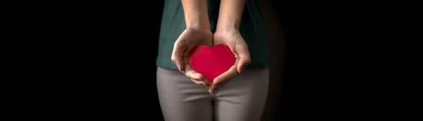 Mãos femininas com coração vermelho. Seguro de saúde, dia do doador de órgãos e conceito de caridade. Banner com foto de fundo preto — Fotografia de Stock
