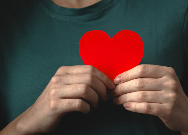 Руки, дающие любовь и держащие красное сердце. Йонг держит бумажное сердце близко к телу. Страхование жизни, мир сердца и психического дня