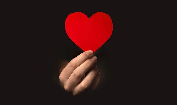 Hand holding red heart on black background. Health insurance, organ donor day, charity photo — Stock Photo, Image